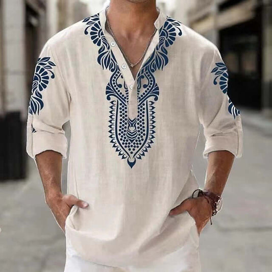 Man wearing stylish white beach long-sleeved shirt with blue floral embroidery, perfect for seaside adventures.