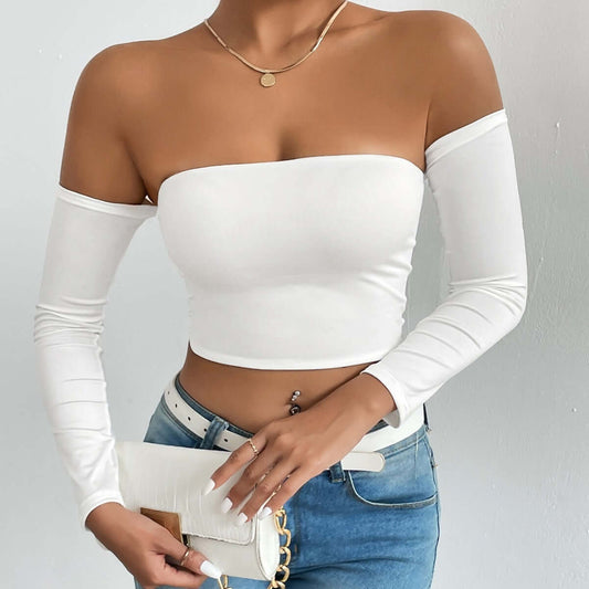 Woman wearing a white off-shoulder top with blue jeans, holding a purse. Fashionable and trendy look for casual outings.