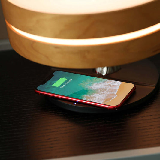 All in one Intelligent Desk Lamp with a Music Box and Wireless Charger, charging a smartphone on a modern workspace.