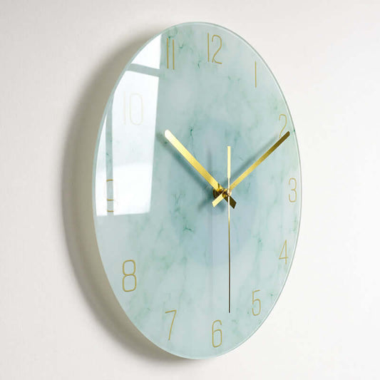 Elegant glass wall clock with gold accents and a soft green marble design, perfect for modern home decor.