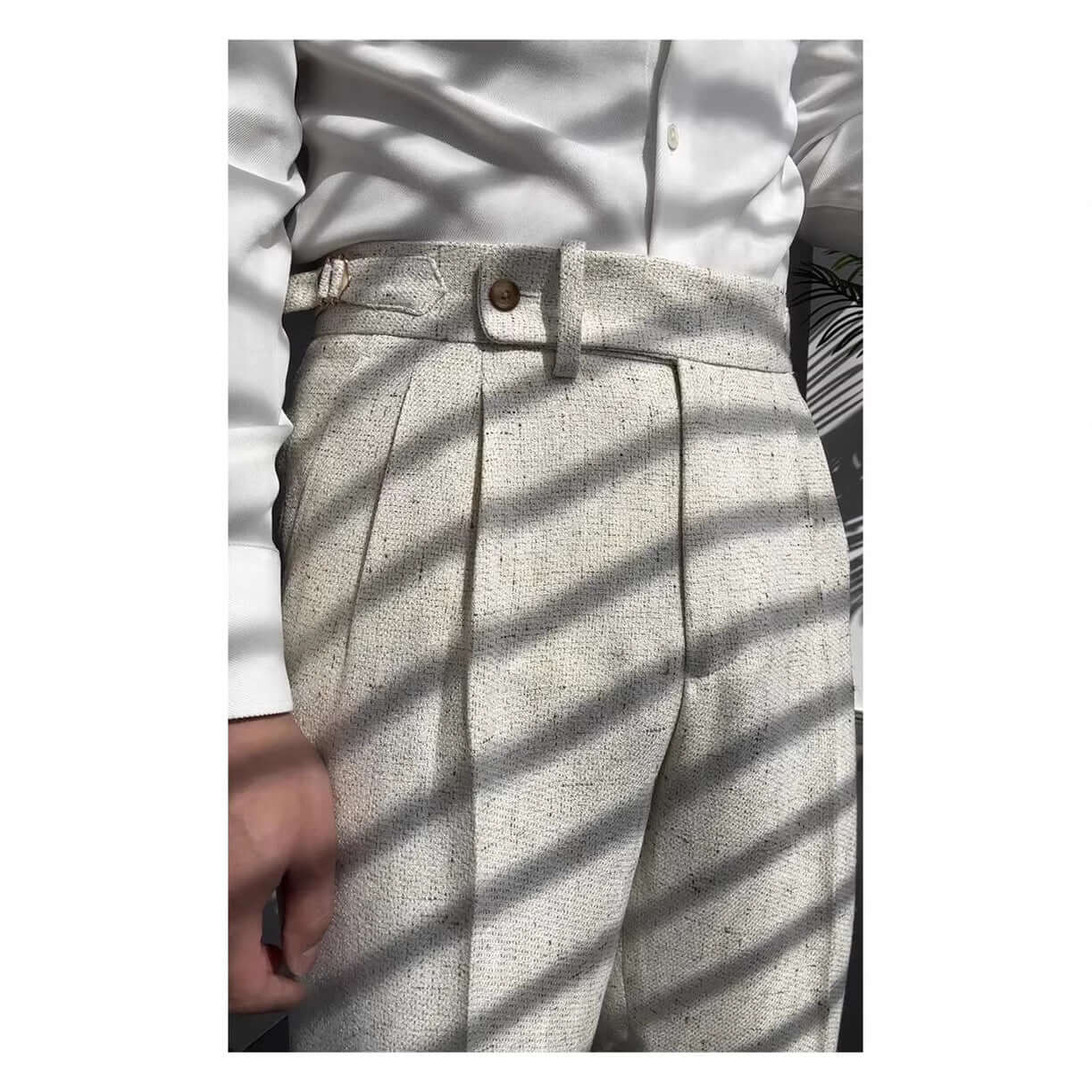 Close-up of stylish straight legged trousers in a light color, paired with a white button-up shirt, perfect for a versatile wardrobe.