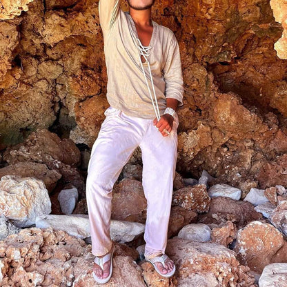 Fashionable lace up T-shirt paired with white pants, perfect for casual outings or relaxing at home, worn in a rocky natural setting.