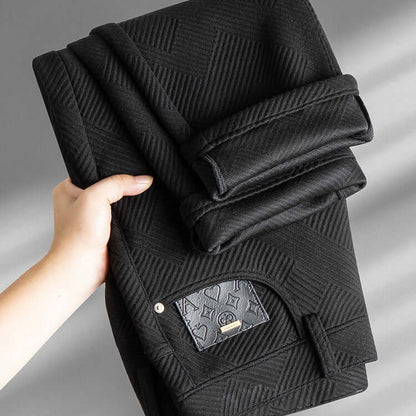 Hand holding folded black Jacquard Trousers, showcasing intricate woven texture, perfect blend of trendy comfort and style for men.