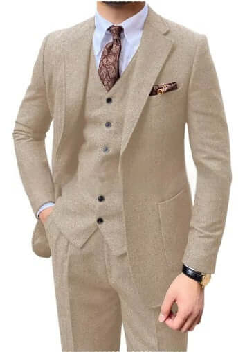 Man wearing 3-piece beige herringbone suit with tie, showcasing elegance and style.