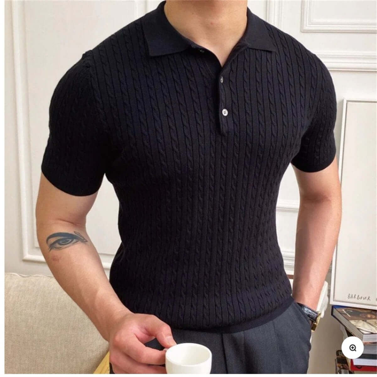 Man wearing a black short-sleeved polo shirt with a textured design, holding a white cup, showcasing casual style and comfort.