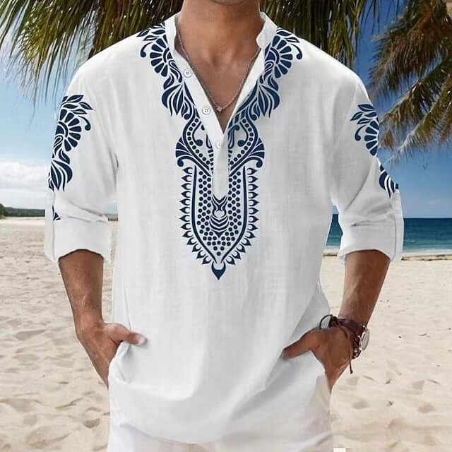 Man wearing stylish beach long-sleeved shirt with intricate blue patterns, perfect for seaside fashion, standing on a sandy beach.