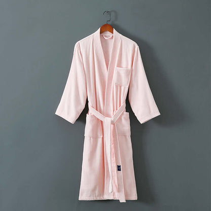 Soft pink unisex spa robe made from cotton and mink fabric, hanging on a wooden hanger against a gray background.