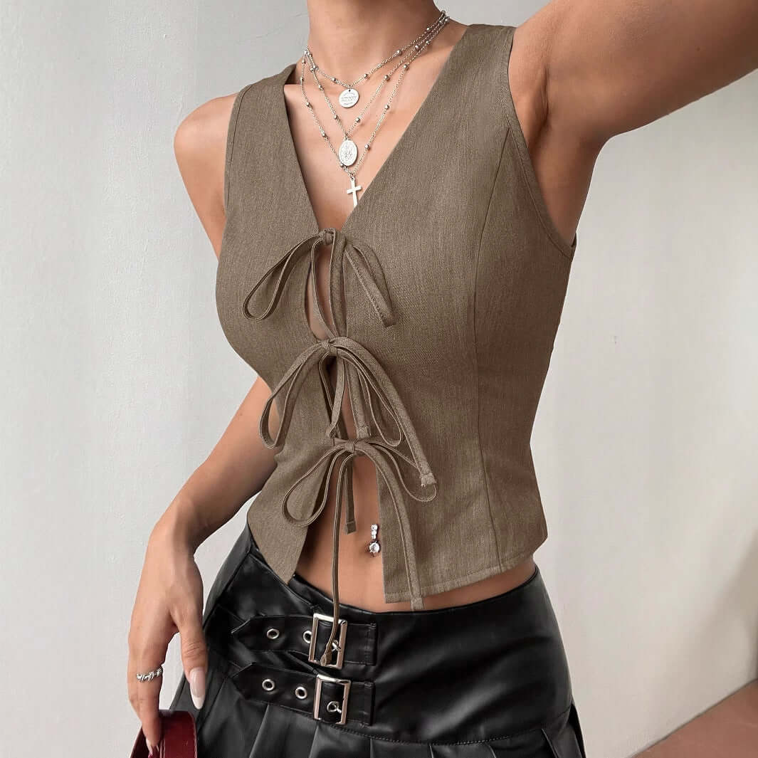 Stylish khaki front lace-up top with sleeveless design, paired with black leather skirt. Perfect for trendy, sleek fashion statement.