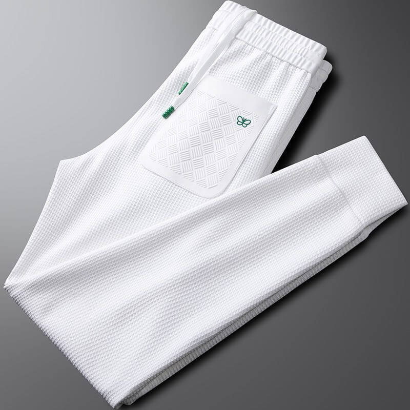 White premium sports trousers with a textured design, elastic waistband, and pocket detailing for men.