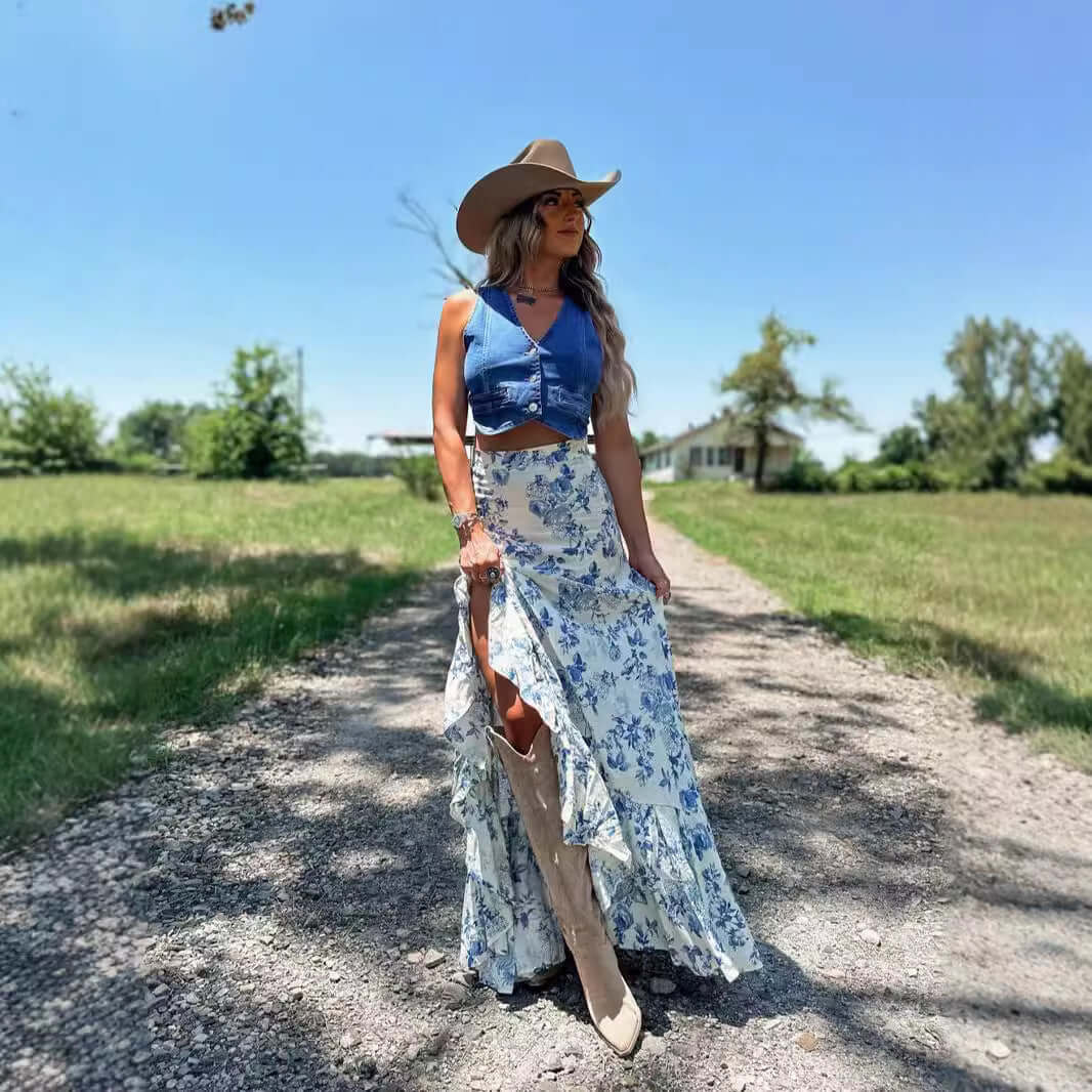 Woman in a blue floral skirt and cowboy hat walking on a sunny rural path