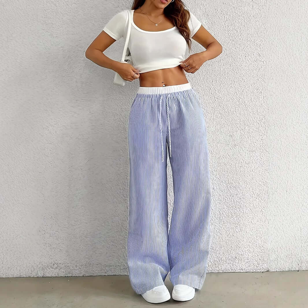 Woman wearing Ladies Stripe Trousers in light blue with a white top, showcasing relaxed fit and lightweight design for stylish wearability.