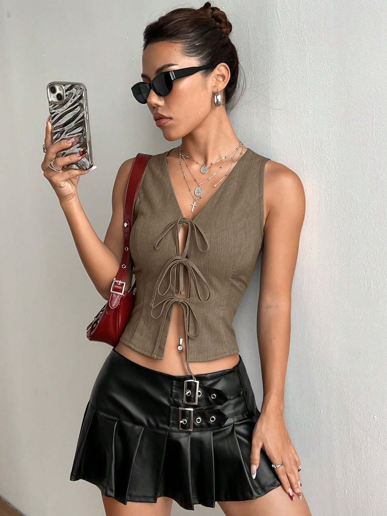 Woman wearing a sleeveless Front Lace Up Top in khaki, paired with a black skirt, showcasing a trendy and stylish look.