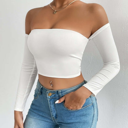 Woman wearing an off-shoulder white crop top paired with high-waisted blue jeans showcasing a stylish casual outfit