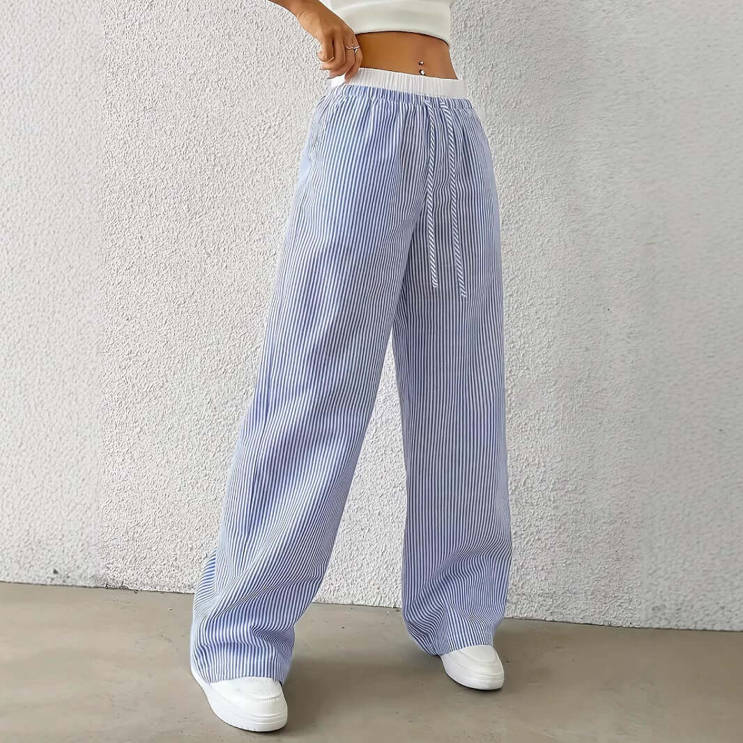 Woman wearing blue Ladies Stripe Trousers with white vertical stripes, showcasing high-quality polyester and stylish design.