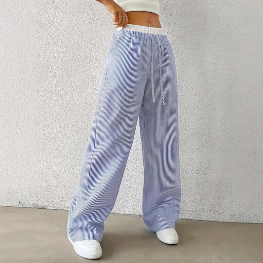 Woman wearing blue Ladies Stripe Trousers with white vertical stripes, showcasing high-quality polyester and stylish design.