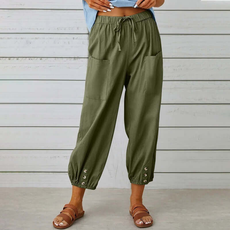 Woman wearing comfortable Ladies Linen Trousers in olive green, featuring front pockets and ankle button detailing.