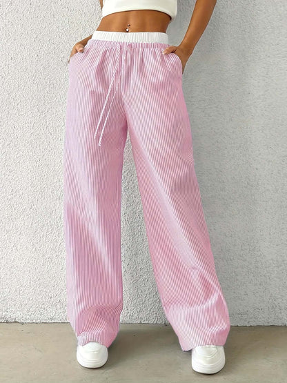 Woman wearing pink Ladies Stripe Trousers with a white waistband, showcasing a fresh and sweet style in a relaxed fit.