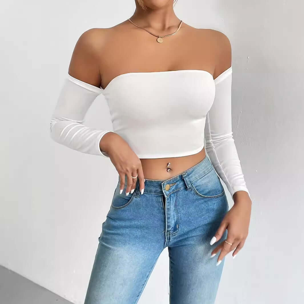 Woman wearing stylish white off-shoulder crop top with long sleeves and blue jeans.