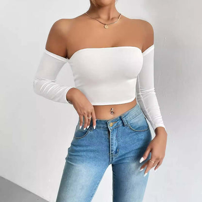 Woman wearing stylish white off-shoulder crop top with long sleeves and blue jeans.