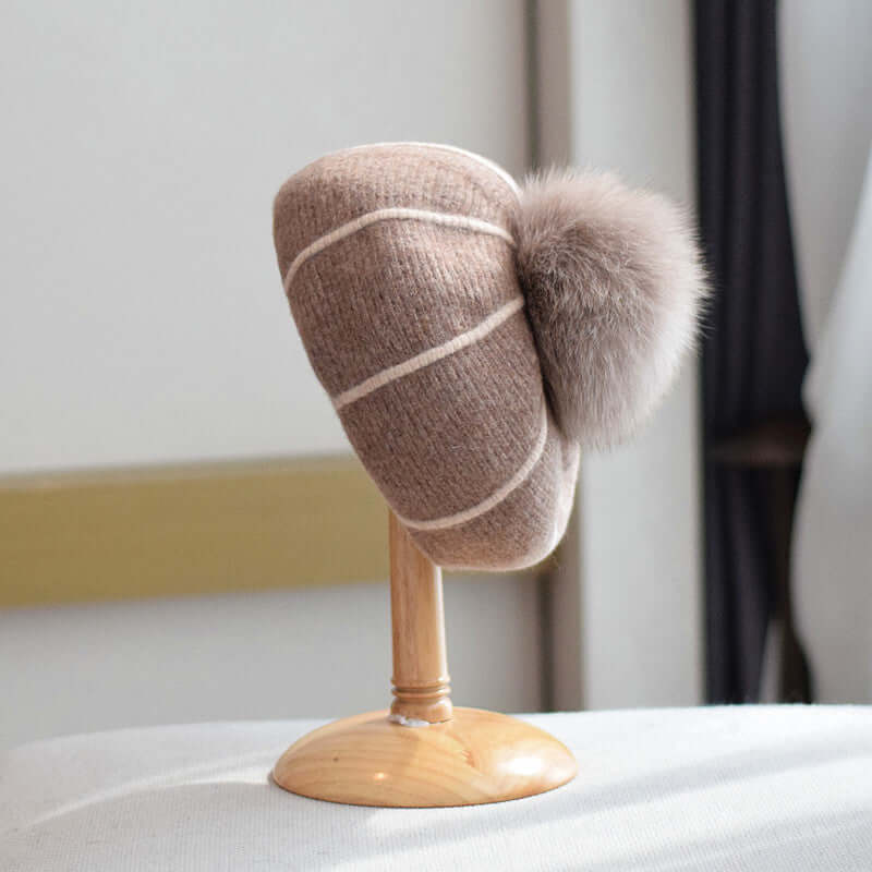 Stylish Beanie with Fur Ball showcased on a wooden stand, perfect for keeping cozy in winter.