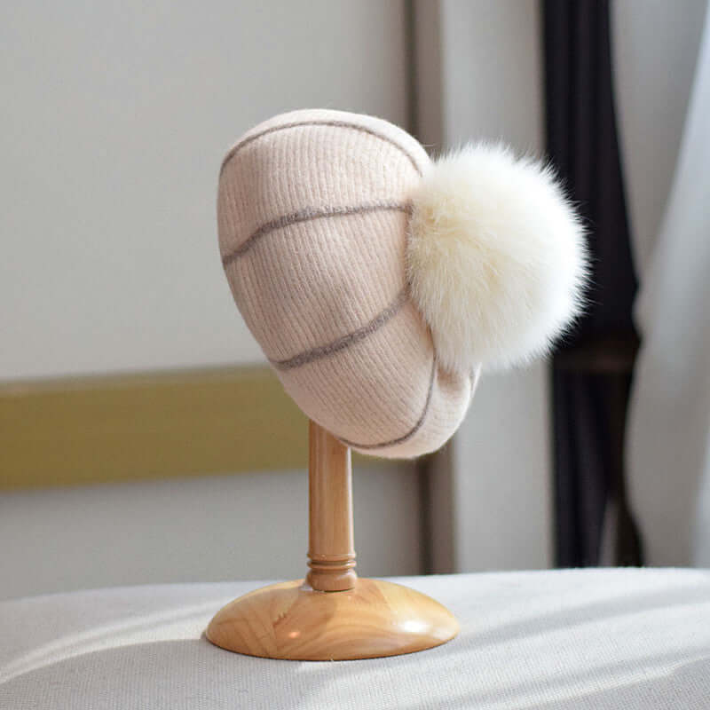 Cozy Beanie with Fur Ball displayed on a wooden stand, ideal for winter fashion and warmth.