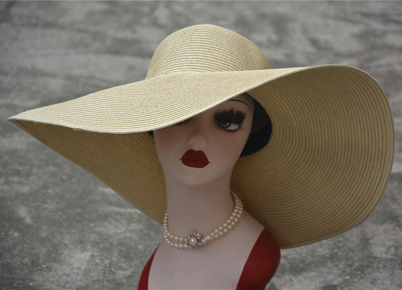 Big straw hat on a mannequin with oversized brim, exuding elegance for summer outings and sun protection.