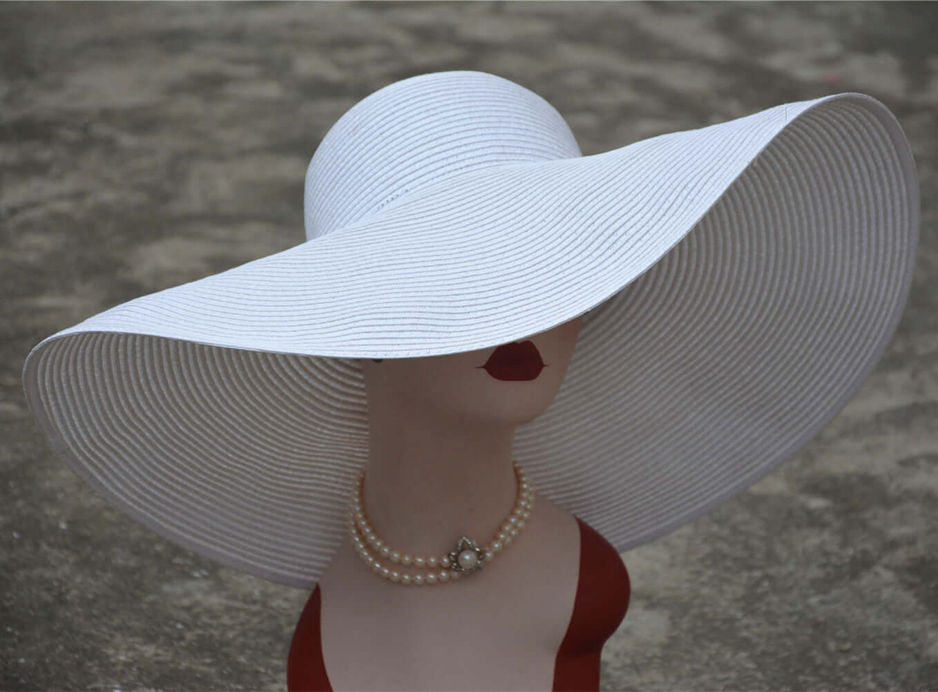 Elegant white big straw hat providing sun protection, showcased on a mannequin with a pearl necklace.