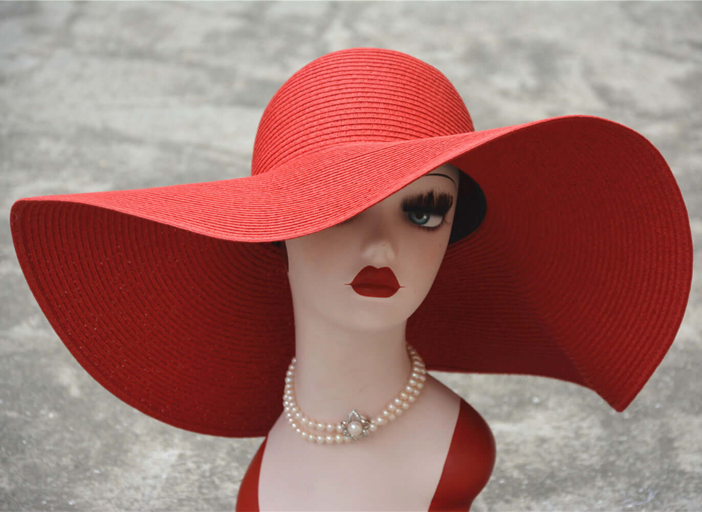 Stylish big straw hat on a mannequin with a bold red design, perfect for sunny days at the beach or park.