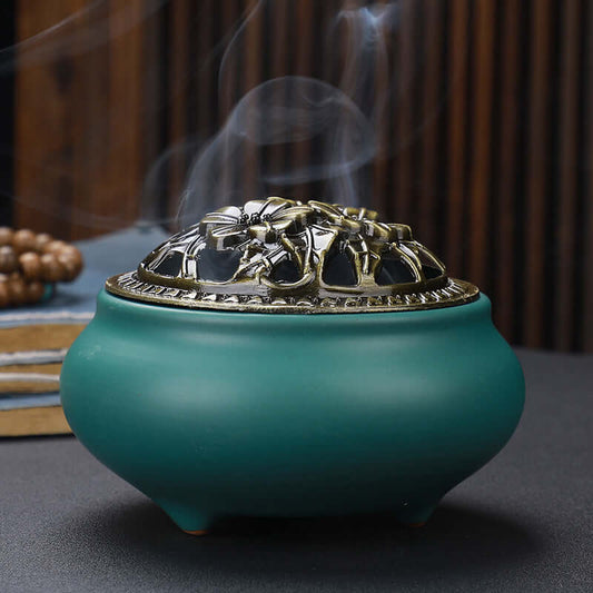 Ceramic incense burner with copper lid, featuring intricate design and smoke for a calming ambiance.