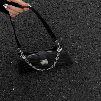 Black Baguette Handbag with chain detail on textured ground, showcasing faux leather and medium size perfect for essentials.