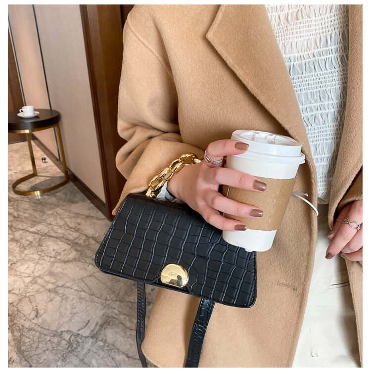 Woman holding a coffee cup and wearing a stylish Crossbody Messenger Bag Purse in black with a chic textured design.