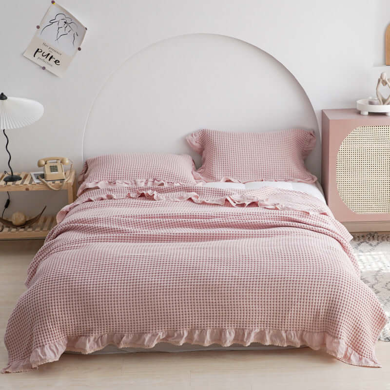 Cozy Plaid Quilt in soft pink, enhancing bedroom aesthetics with ruffled edges and stylish decor accents.