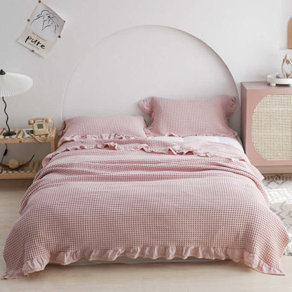Cozy Plaid Quilt in soft pink, enhancing bedroom aesthetics with ruffled edges and stylish decor accents.