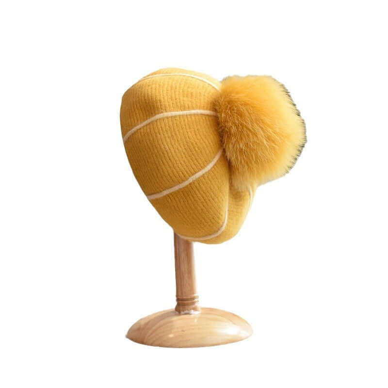 Stylish yellow Beanie with Fur Ball displayed on a stand, perfect for winter fashion and warmth.