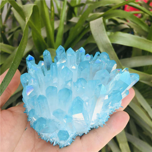 Hand holding a breathtaking blue crystal healing stone among greenery, symbolizing wellness and natural beauty.