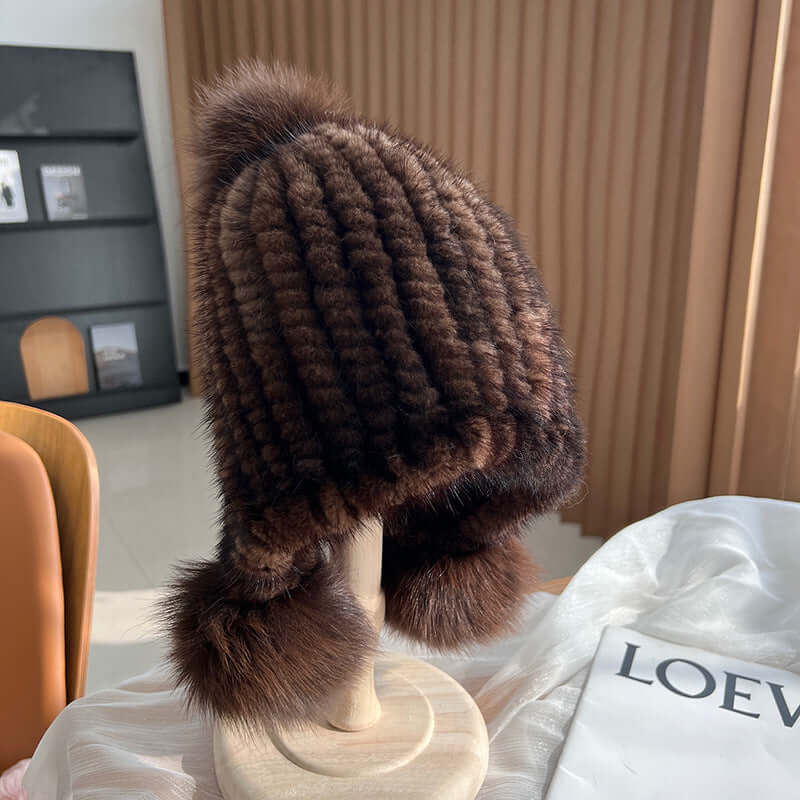Stylish brown Ear Muffs Hat featuring a plush texture and fur pom-poms, perfect for winter warmth and fashion.