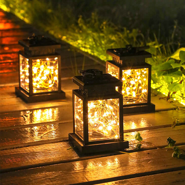 Outdoor illuminated path with three glowing wind up lanterns, providing eco-friendly lighting solutions for garden or camping.