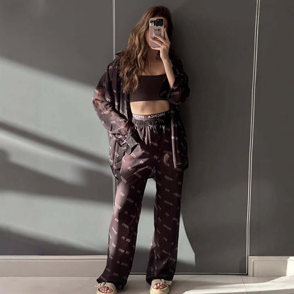 Woman wearing a stylish black jumpsuit with chiffon overlay, featuring unique text pattern, standing in a modern setting.