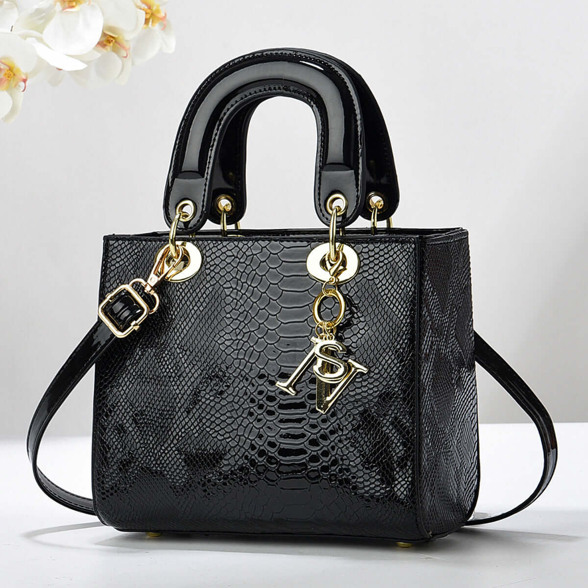 Elegant black textured handbag with gold accents and detachable strap, featuring a sleek design suitable for sophisticated outings.