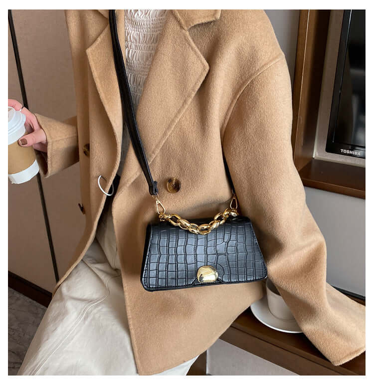 Woman with a black Crossbody Messenger Bag Purse made of PU material, chain strap design, wearing a beige coat, ideal for stylish travel.