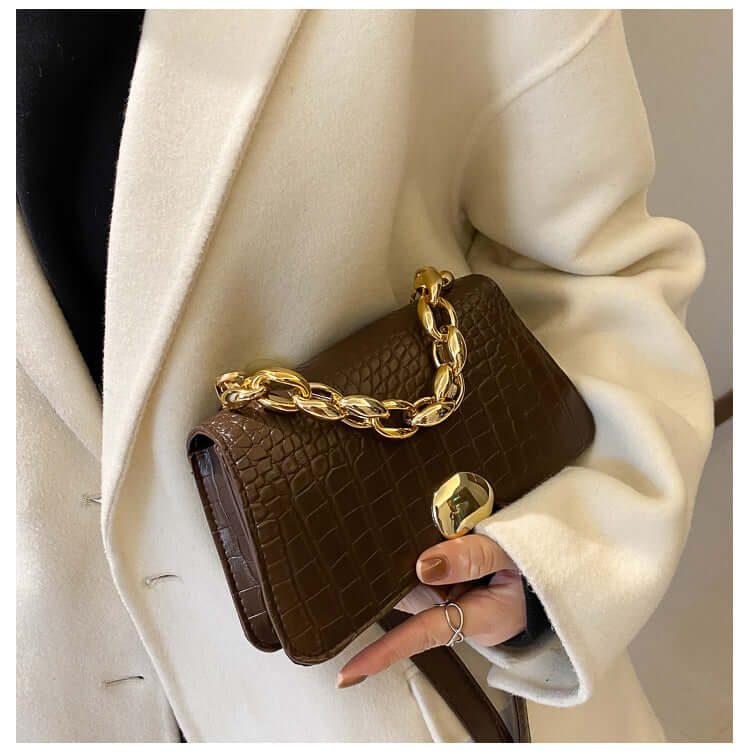 Fashionable woman holding a dark brown Crossbody Messenger Bag Purse with gold chain detail, perfect for chic on-the-go style.