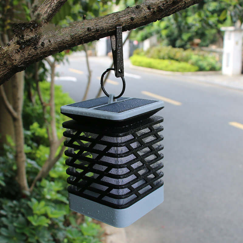 Rectangular lantern hanging from a tree branch, enhancing outdoor ambiance with its elegant design and inviting glow.