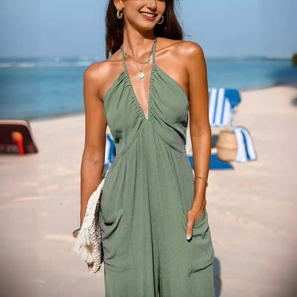 Woman wearing a Back Open Jumpsuit in olive green, posing on a beach with blue ocean backdrop, epitomizing summer style and comfort.