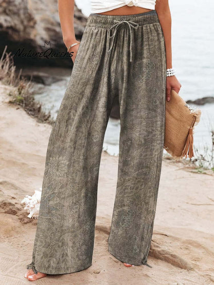 Person wearing wide-leg trousers in gray brushed milk silk, standing outdoors near a beach.