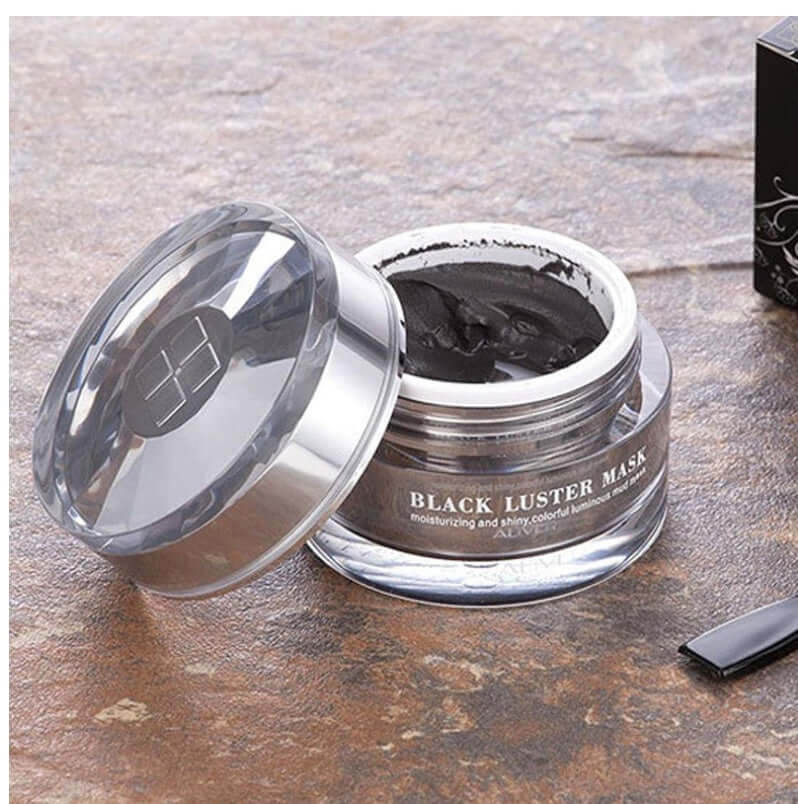 Open jar of luxurious black facial mud mask on textured surface, highlighting natural ingredients and deep cleansing properties for healthy skin.