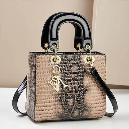 Chic faux snakeskin handbag with black glossy handles, featuring gold accents and adjustable strap, ideal for stylish urban look.