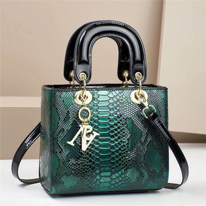 Green snake pattern handbag with black handles and gold accents, featuring stylish, modern design.