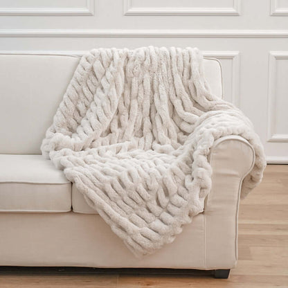 Cozy faux fur pelt blanket draped over a beige couch, adding warmth and style to modern living room decor.