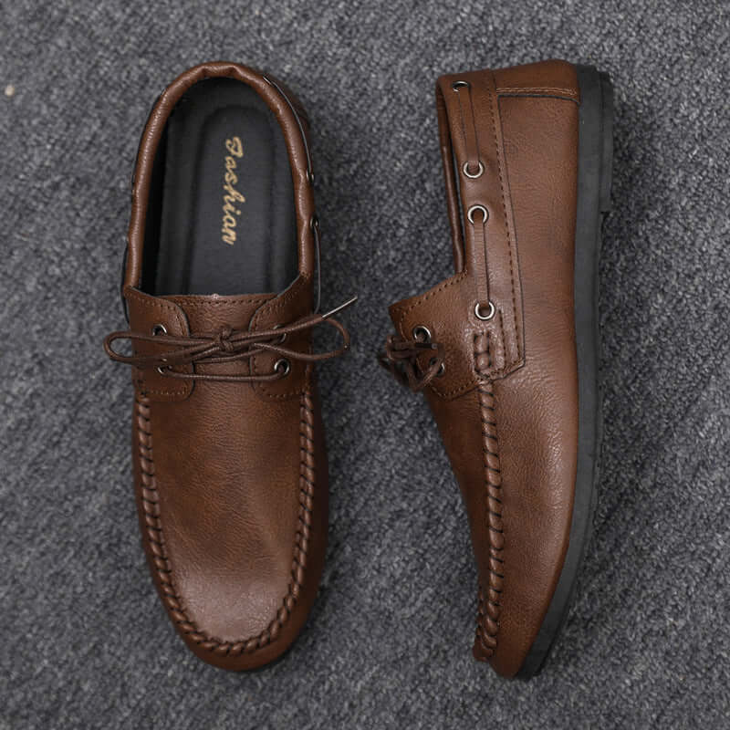 Brown faux leather loafers with soft lining on a grey background, showcasing durable craftsmanship and elegant design.