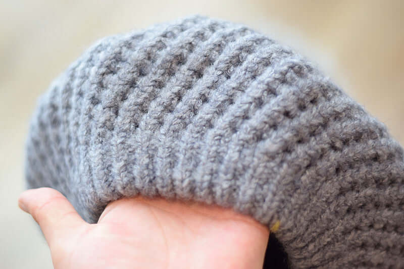 Close-up of a soft, gray knitted Fur Ball Hat showcasing its texture and cozy design.